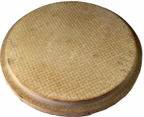 Runder, flacher Stein mit einer genoppten Oberfläche, geeignet für den Brennraum. Produkt von Wolf, verwendet in spezifischen Heizsystemen.
